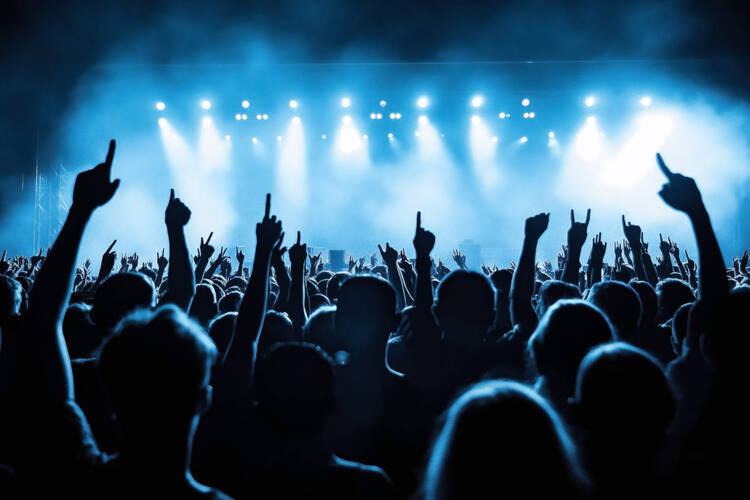 Das Publikum hebt die Arme und winkt in die Richtung der Bühne auf einem Konzert.