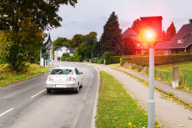 Ein Auto wird im Ortseingang von einer Radarfalle geblitzt.
