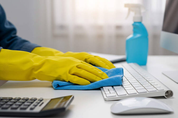 Eine Person wischt mit einem Tuch über die Tastatur.