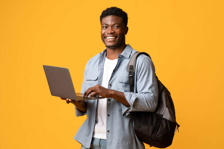 Ein Mann hält ein Laptop in der Hand und lächelt. 