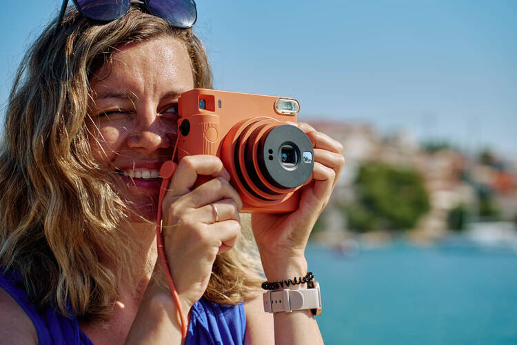 Eine Frau fotografiert mit einer Sofortbildkamera. 