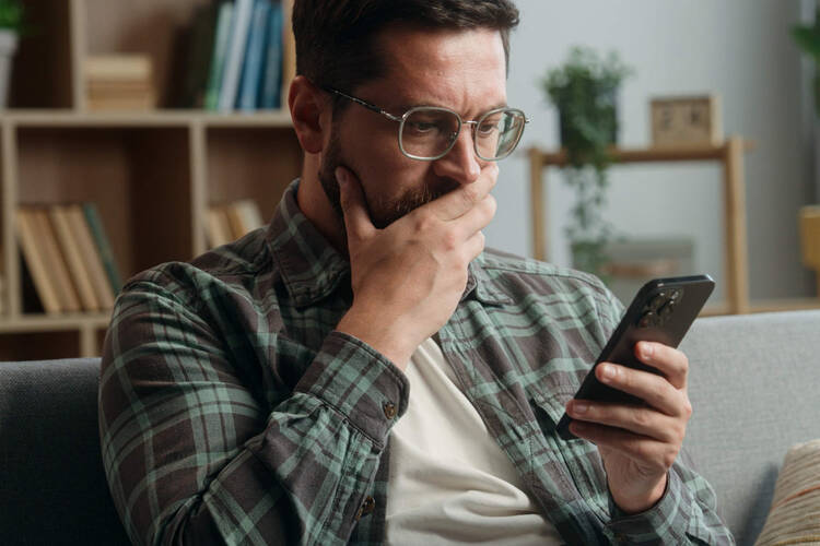 Ein Mann blickt erschrocken auf sein Handy. 