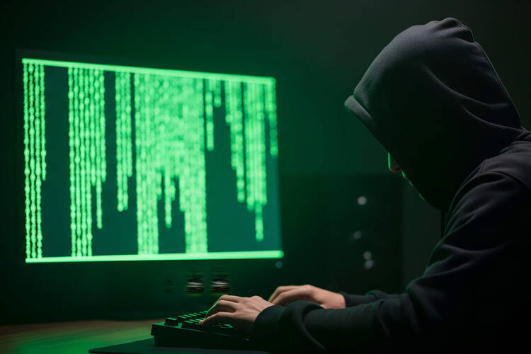 Eine Hacker-Gestalt sitzt vor einem Computer.