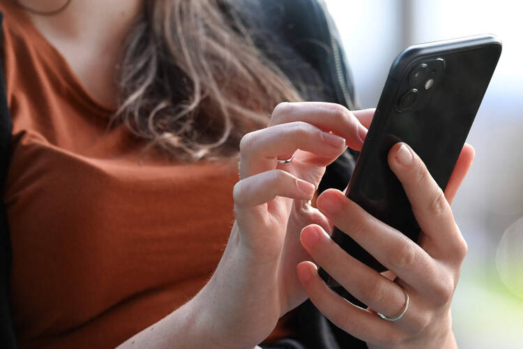 Eine Frau hält ein Smartphone in der Hand. 