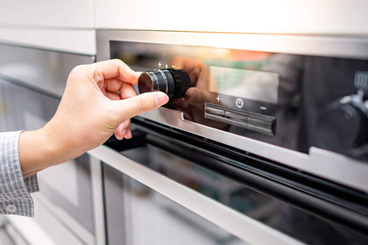 Eine Person schaltet den Backofen ein.