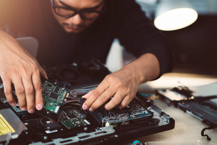 Ein Mann hantiert an einer Festplatte im Notebook-Gehäuse herum.