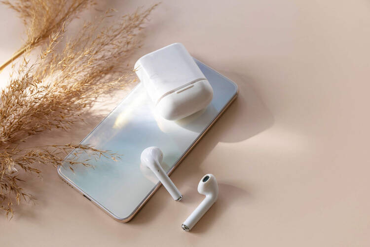 Ein iPhone liegt zusammen mit Kopfhörern auf einem Tisch.