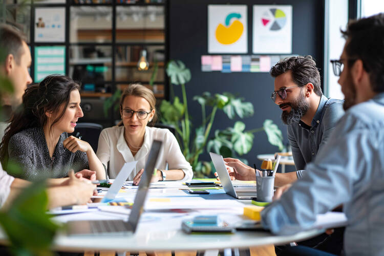 Eine Gruppe von Personen sitzt an einem Tisch und hält ein Meeting.