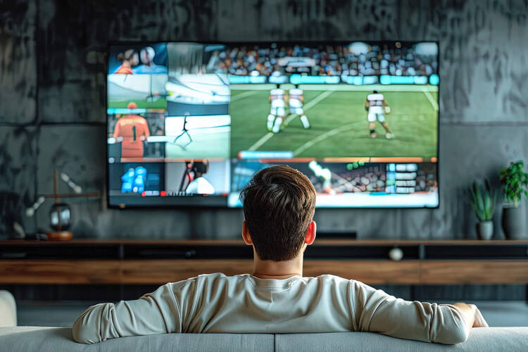 Ein Mann sitzt auf dem Sofa und schaut Fußball auf dem Fernseher.