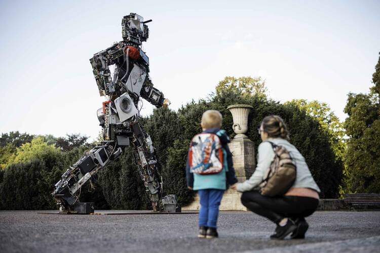 Ein Kind und eine Frau schauen auf eine Skulptur aus Elektroschrott.