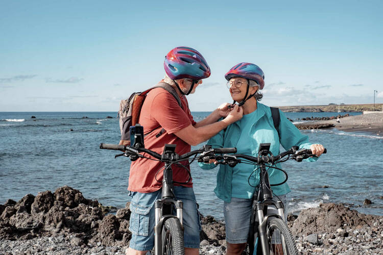 Älterer Herr macht den Fahrradhelm von Frau zu.