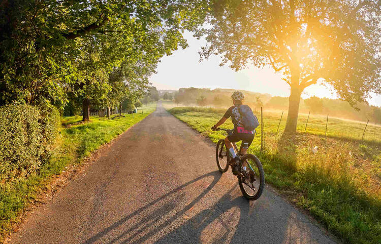 Mountainbikerin fährt durch Feld bei Sonnenuntergang