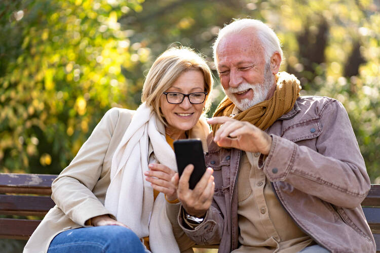 Älteres Ehepaar schaut auf Smartphone draußen