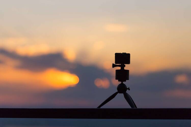 GoPro steht auf kleinem Stativ vor Sonnenuntergang