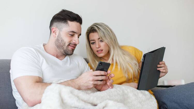 Paar auf Sofa schaut auf Smartphone