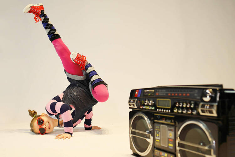Mädchen macht Breakdance im Hintergrund Boombox
