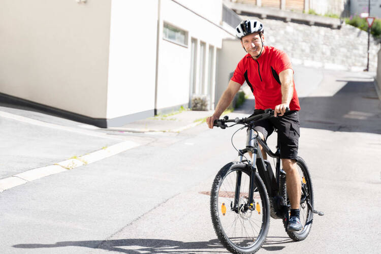 Mann mit Helm fährt Fahrrad auf der Straße.