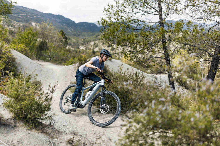 Frau fährt mit Mountainbike über Gravelpiste.