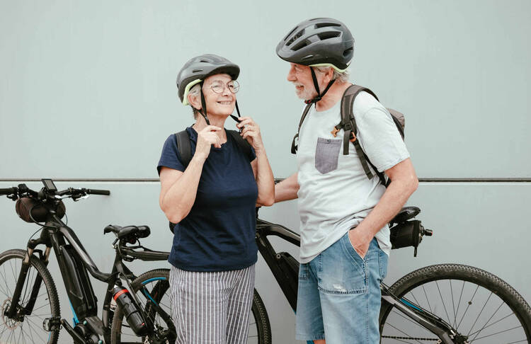 Zwei ältere Menschen stehen von Fahrrädern und lächeln.