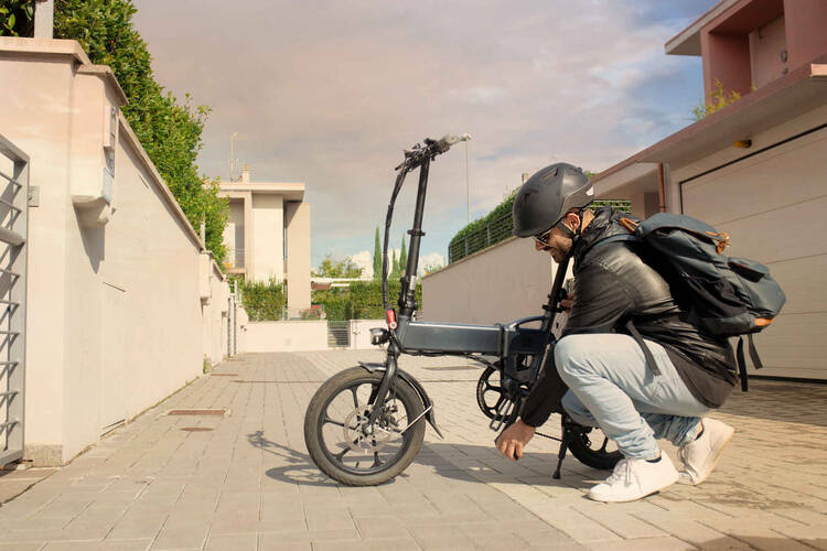 Mann mit Helm setzt Akku an faltbarem E-Bike ein.