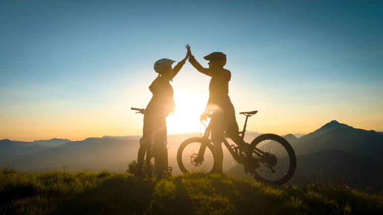 zwei Fahrradfahrer in den Bergen geben High-Five