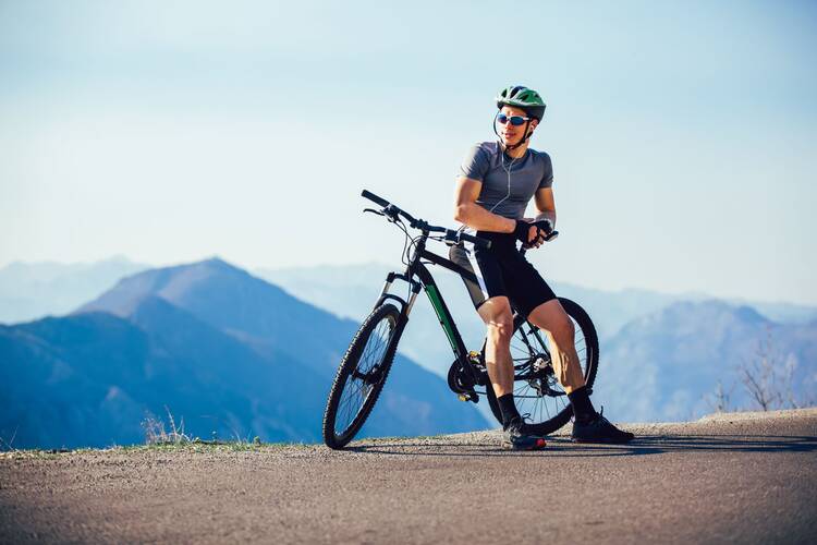 Mann auf Crossbike steht in der Landschaft