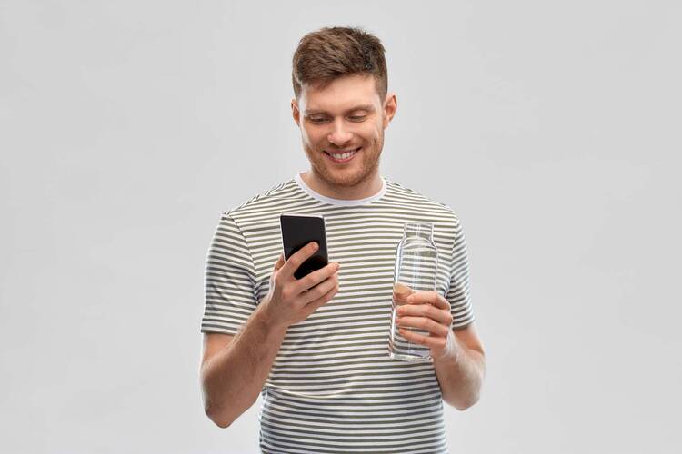 Mann im geringelten Shirt hält Wasserflasche in einer Hand und schaut lächelnd auf das Smartphone in der anderen Hand