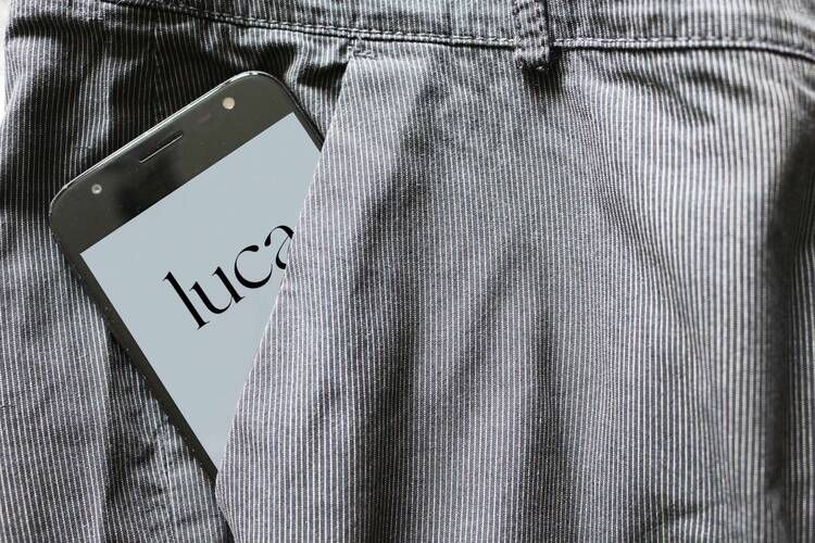Smartphone mit Luca-Symbol auf Display schaut halb aus grauer Hosentasche hervor