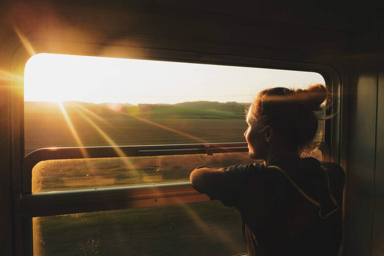 Frau schaut auf den Sonnenuntergang aus dem Zugfenster