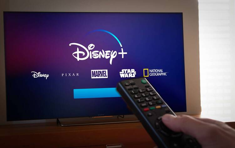 Fernseher mit Disney+ Symbol und Fernbedienung im Vordergrund