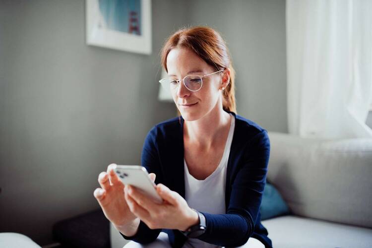 Frau sitzt auf Sofa mit Smartphone in der Hand