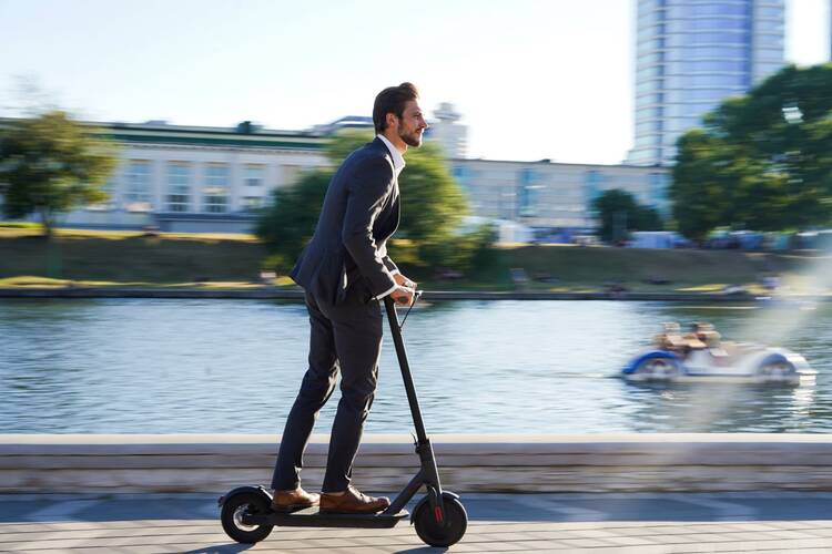 Mann im Anzug fährt auf einem E-Scooter