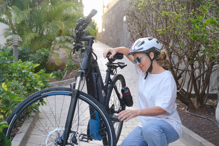 Frau hockt neben Ihrem Fahrrad und prüft die Reifen.