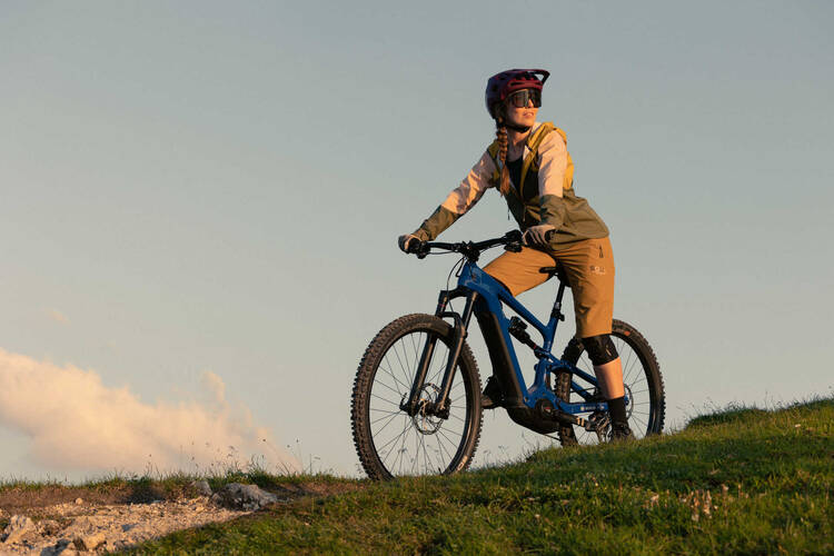 Frau mit Helm auf Mountainbike fährt Berg hinunter.
