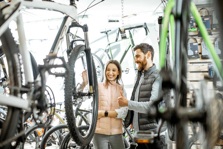 Mann und Frauen stehen vor E-Mountainbike und beraten sich.