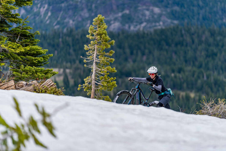 Frau schiebt Mountainbike verschneiten Berg hoch.
