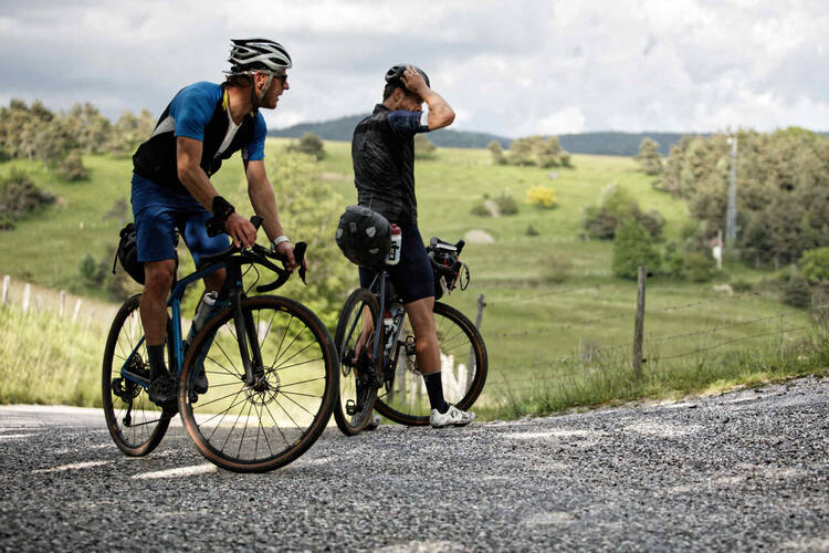 Zwei Männer auf Gravelbike schauen sich die Natur an.