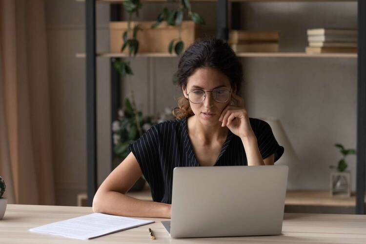 Frau sitzt konzentriert vor Lapto