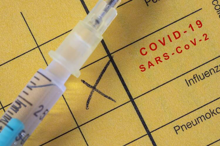 Impfpass in Nahaufnahme mit Covid-Impfstempel und Spritze, die darauf liegt