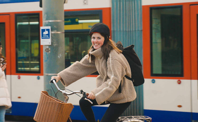 Frau auf Fahrrad fährt neben Zug.