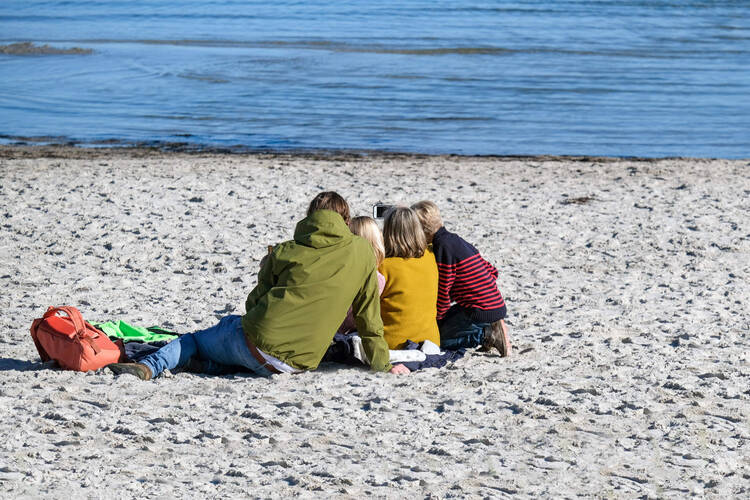Familie sitzt am Strand und macht ein Selfie