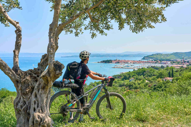 Mann steht neben Fahrrad und blickt über Stadt.