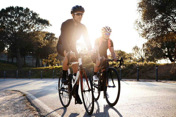 Mann und Frau mit Helm fahren auf Rennrad.