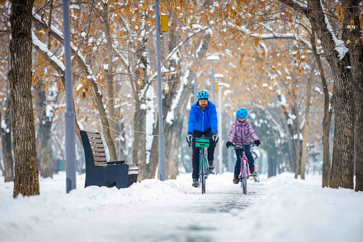 Mann und Kind fahren Fahrrad im Schnee.