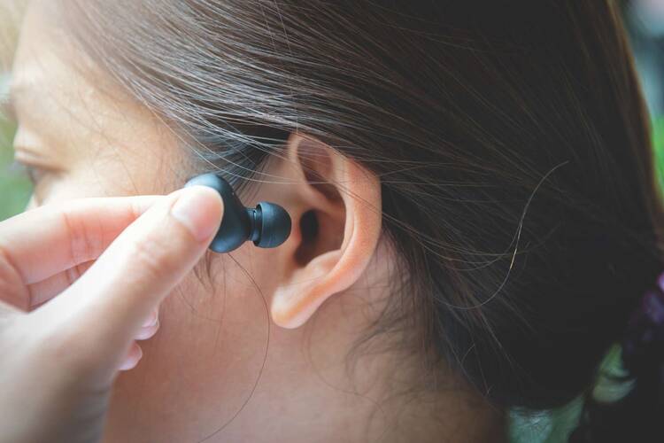 Frau setzt schwarze In-Ear-Kopfhörer in ihr Ohr ein