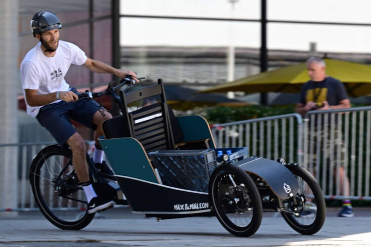 Mann mit Fahrradhelm fährt auf Elektro Lastenrad