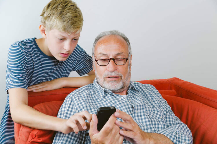 Älterer Mann lässt sich Handy von Kind erklären