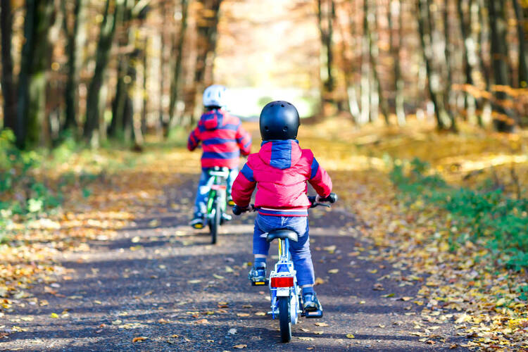 Kinder fahren Fahrrad mit herbstlichem Hintergrund