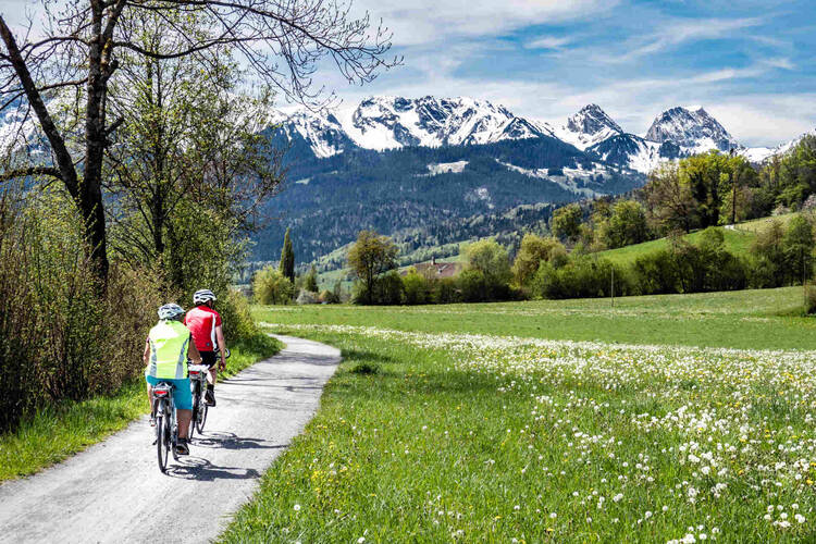 Älteres Paar fährt mit Fahrrädern durch Alpenlandschaft.