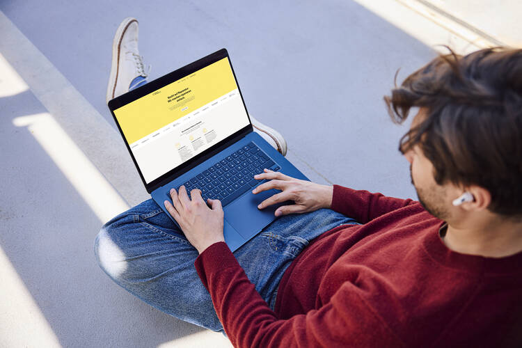 Ein Mann rtuft eine Website auf einem Laptop auf.